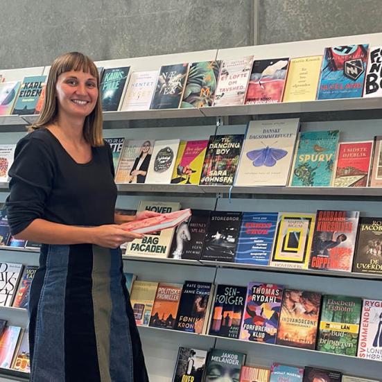 Matilde foran hylden med de nye bøger på Støvring Bibliotek