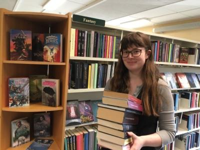 Foto af Katrine med en stak Fantasy-bøger på Skørping Bibliotek