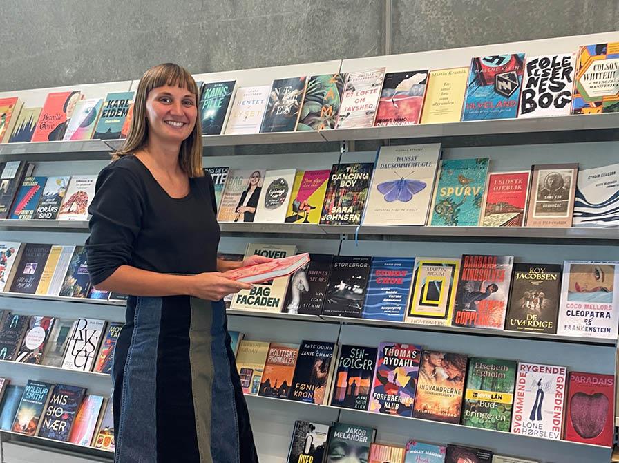 Matilde foran hylden med de nye bøger på Støvring Bibliotek